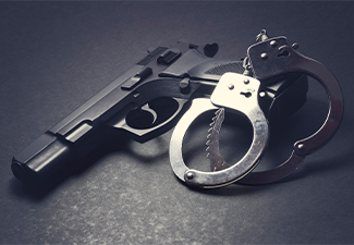 Handgun with handcuffs on dark background, crime concept