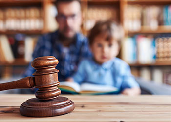 Gavel on table with blurred father and child in background