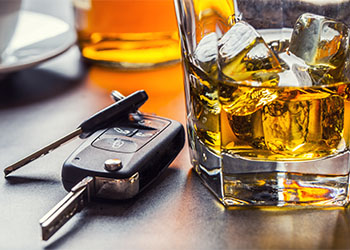 Car keys and glass of alcohol on table