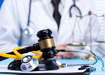 Stethoscope and gavel in table with doctor in background