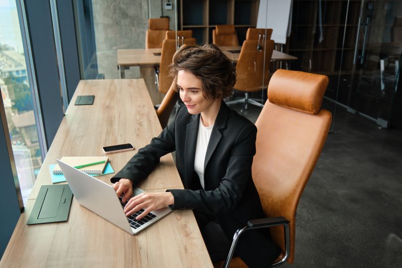 A business professional works on a laptop in a modern office