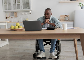 Man in wheelchair looking at document in laptop