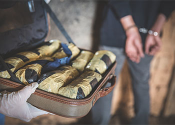 Bag of drug with handcuffed man in background