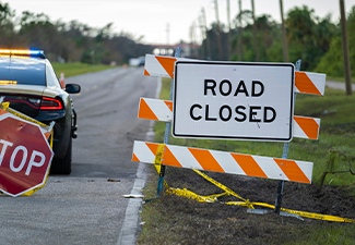 Police patrol car at warning roadworks sign and safety barrier on city street