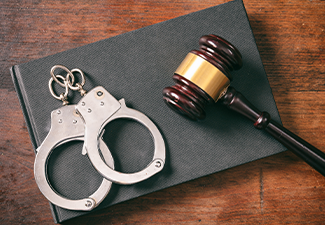 Handcuffs, gavel on book on a wooden background