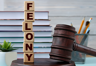 The word FELONY on wooden cubes against the background of the judge's gavel