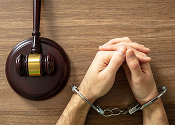 Handcuffed man with gavel on table