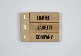 Wooden Blocks Displaying LLC Limited Liability Company on white Background