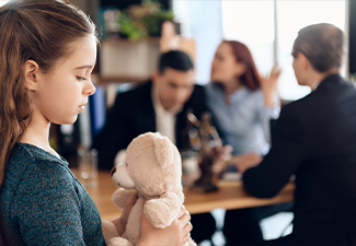 Upset girl with a bear in hand is standing and sad