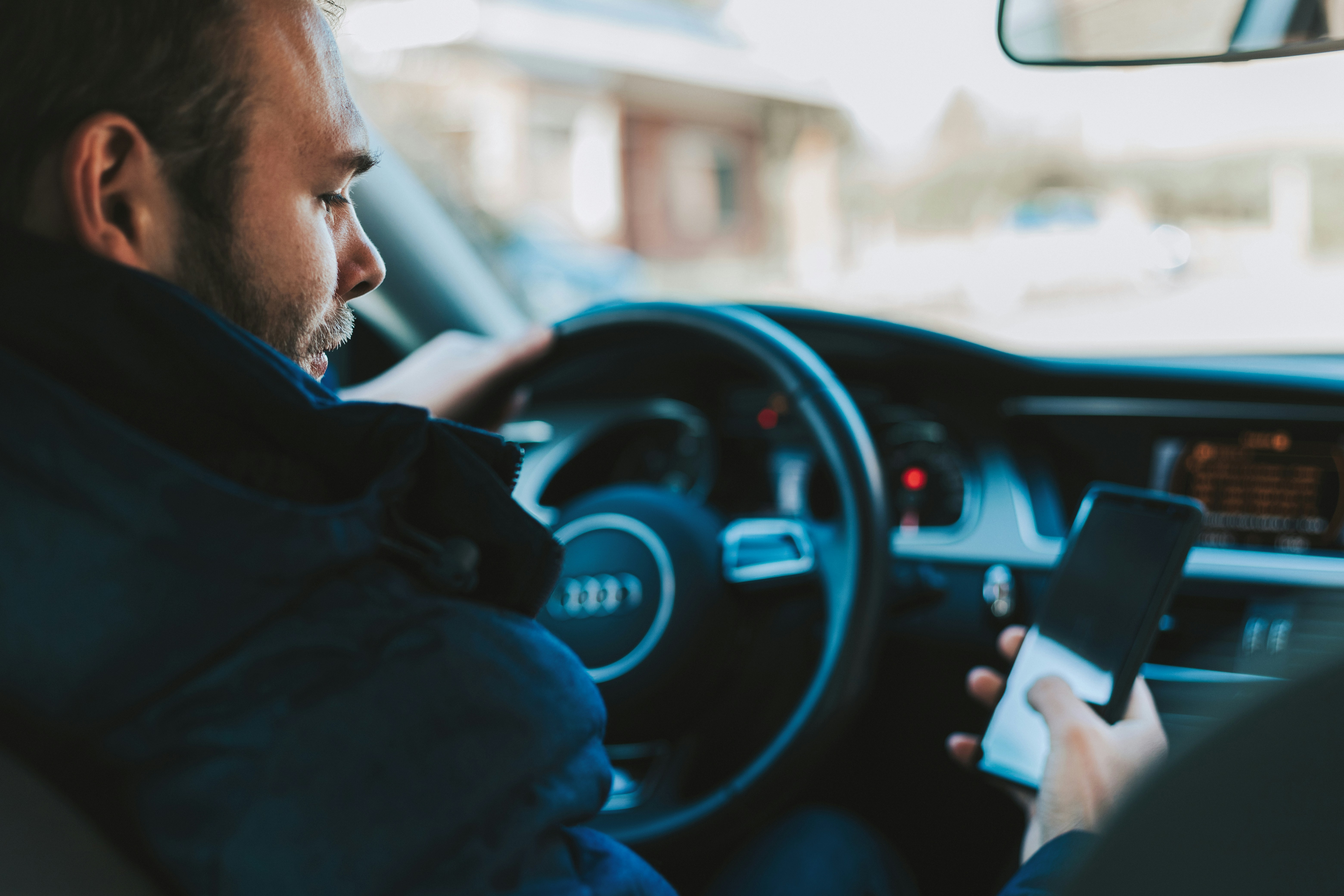 Distracted driver looking at his cell phone while behind the wheel