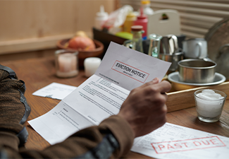 Person holding eviction notice at wooden table with various condiments