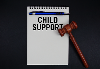 Child Support text written on notepad with gavel on black background