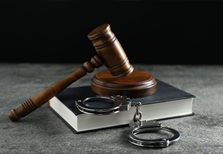Handcuffs, book and judge's gavel on grey textured table, closeup