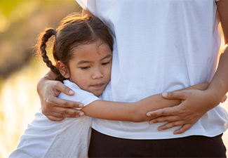 Sad asian child girl hugging her mother in the paddy field with the sunlight