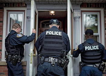 Police officers at front door of a house for search operation