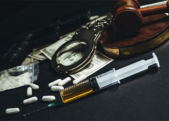 Gavel, handcuffs and drugs on table