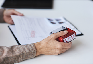 Person holding red rejected stamp while refusing in receiving visa rejection