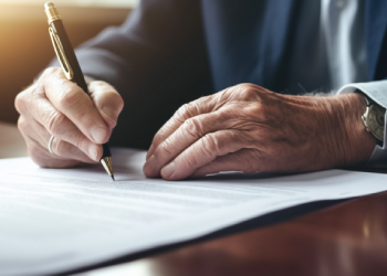 Elderly man examining and signing last will document
