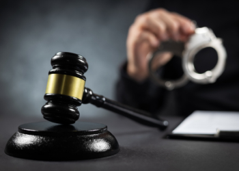 Judge's gavel and handcuffs in hand of an officer