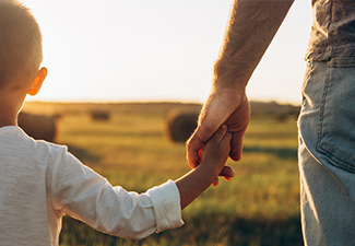 Father's and his son holding hands at sunset field