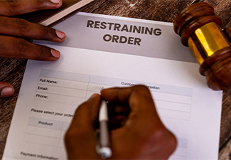 Person Filling Restraining Order Form and Gavel on Table