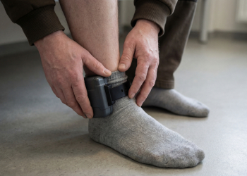 Man under probation adjusting his monitoring device