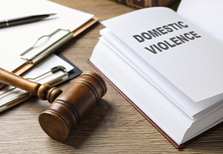 Wooden gavel and domestic violence law book on wooden table