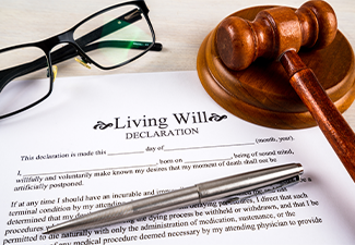 Living will declaration form with pen, gavel and striking block and glasses on top
