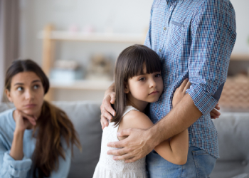 Unhappy mother looking at child hugging dad