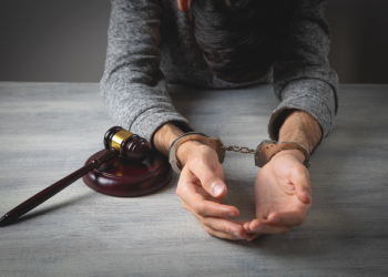Handcuffed man with gavel in table