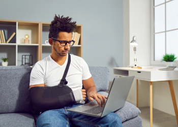 Man with injured arm working on laptop