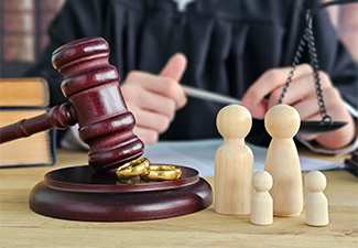 A gavel, small wooden figurines of parents and children, and a judge on a courtroom table