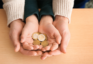 Hands of young man and his son holding coins on wooden table