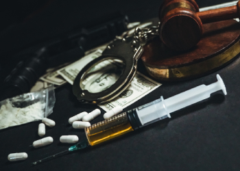 Drugs, handcuff and gavel in table