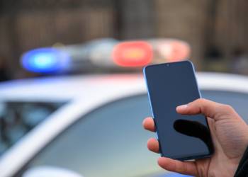 Phone in hand with police car in background