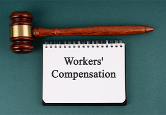 Gavel and notepad with text workers compensation on green background