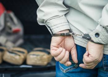 Handcuffed man with seized drug pouches