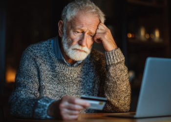 Elder fraud, serious old man looking at financial statement