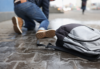 Man with backpack felling on slippery sidewalk in winter closeup