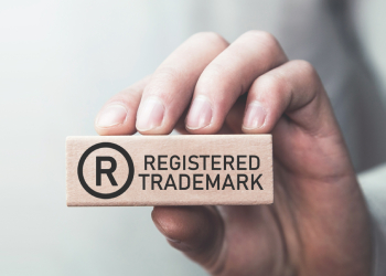 Male hand showing Registered trademark on wooden block.