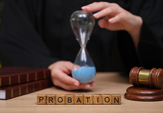 A judge holds an hourglass filled with blue sand, symbolizing time in a courtroom setting