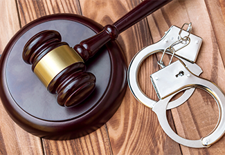 Judge's gavel with handcuffs on the table
