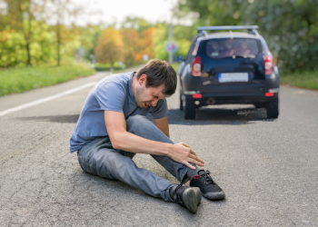 Injured man on road with running away car