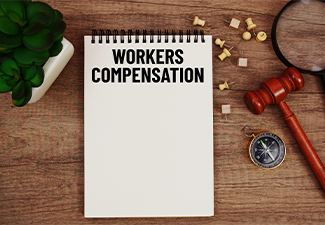 Workers Compensation message written on notepad with wood gavel