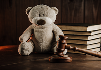 Wooden gavel and teddy bear as symbol of child on a desk