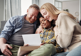 Happy parents embracing their African adoptive son while reading adoption