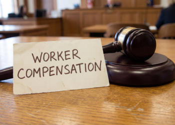 Worker Compensation word on paper sheet with gavel in courtroom