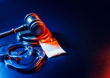 Gavel, handcuffs and drugs in table