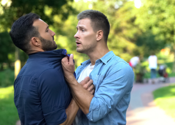 Angry man threatening another male outdoors