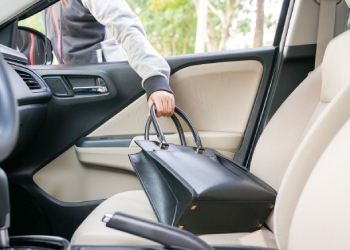 Thief stealing a bag through the window of car